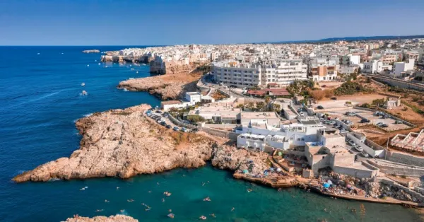  Pobrežie Bari v Apúlii – útesy s plážou a plavcami, biele budovy mesta a tyrkysové more v slnečný deň