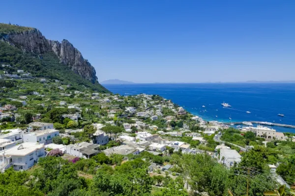 Capri Taliansko, Panoramatický výhľad na ostrov – biele domčeky roztrúsené po svahoch, zeleň, útesy a tyrkysové more